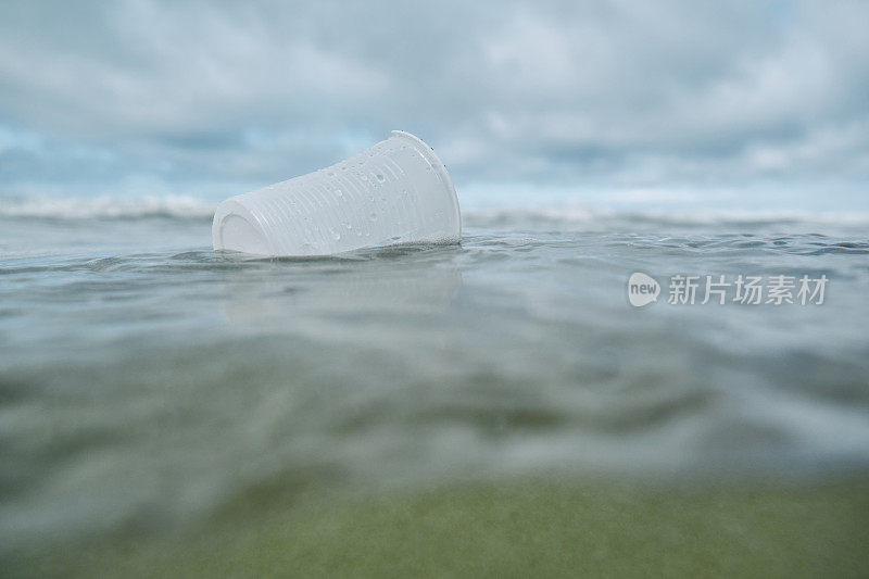 环境问题，废弃的一次性塑料杯漂浮在海里。