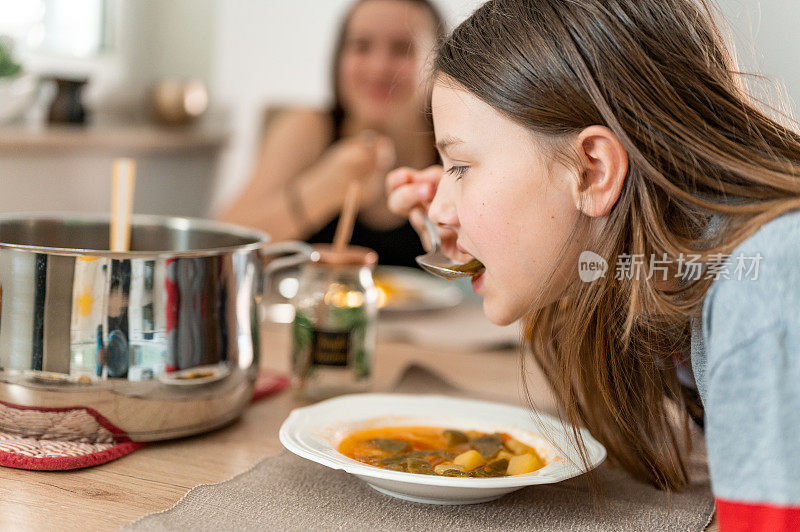 年轻女孩在家里喝蔬菜汤