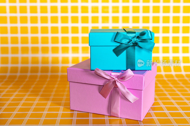 一堆粉色和蓝色礼品盒上的黄色方格背景照片