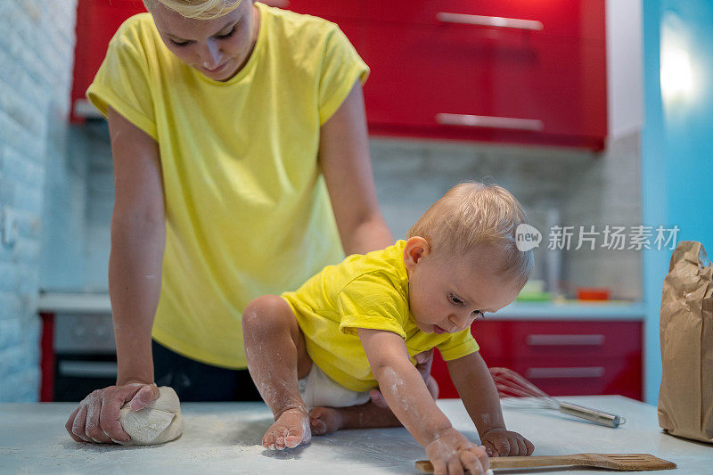 妈妈和儿子正在准备早上一起做饼干的面团。孩子在扔面粉，很高兴。