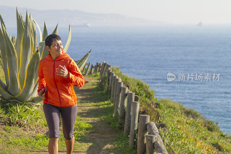 拉丁成年女子沿着海边的木板路跑步