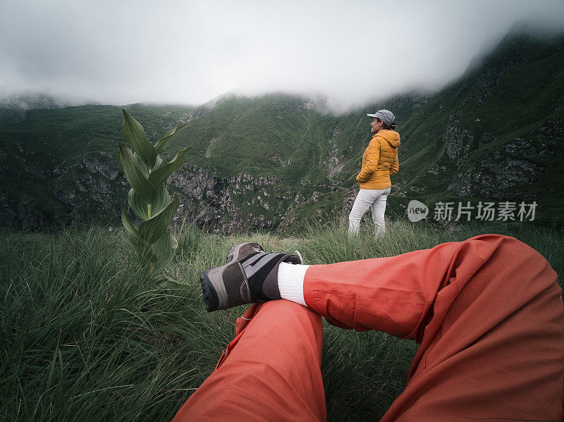 从个人角度看一个人，脚在框架里。回归自然。徒步旅行的游客夫妇在山上看美丽的景色。2019冠状病毒病大流行后的夏日户外享受。社会距离。