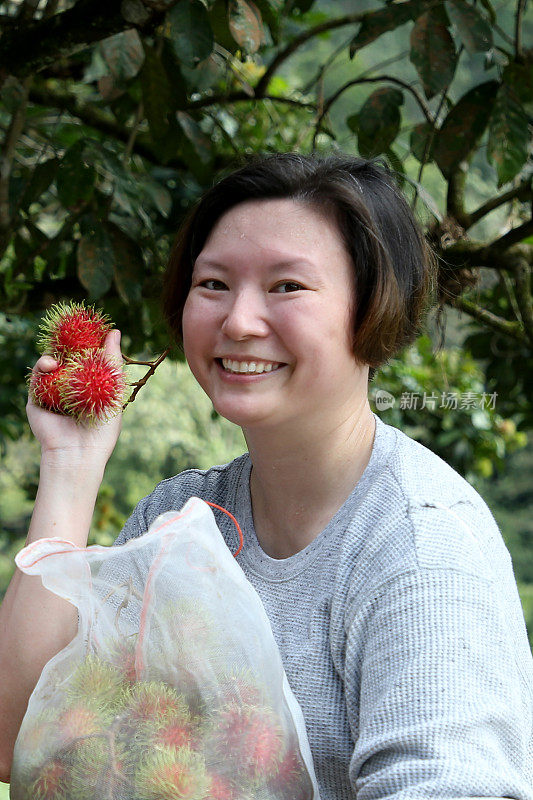 微笑的女人拿着草莓站在植物旁边