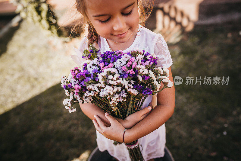 可爱的小女孩拿着紫色的花给她的妈妈