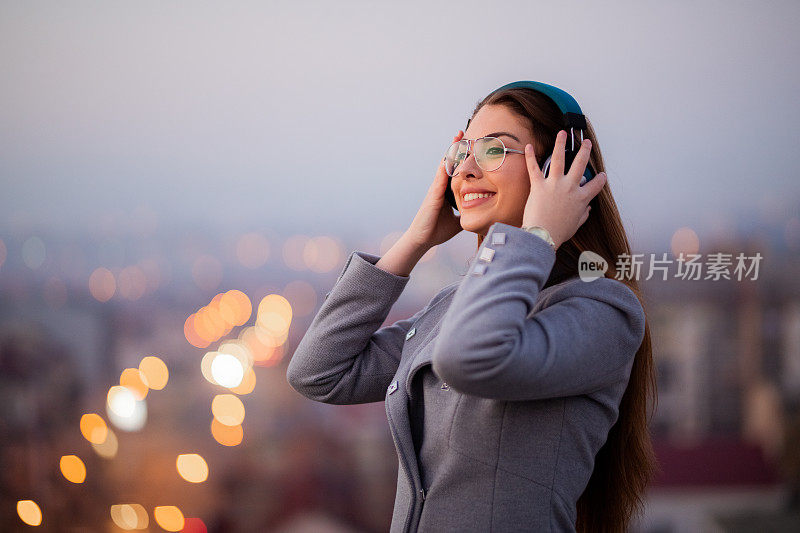 漂亮的年轻女人在屋顶上听音乐