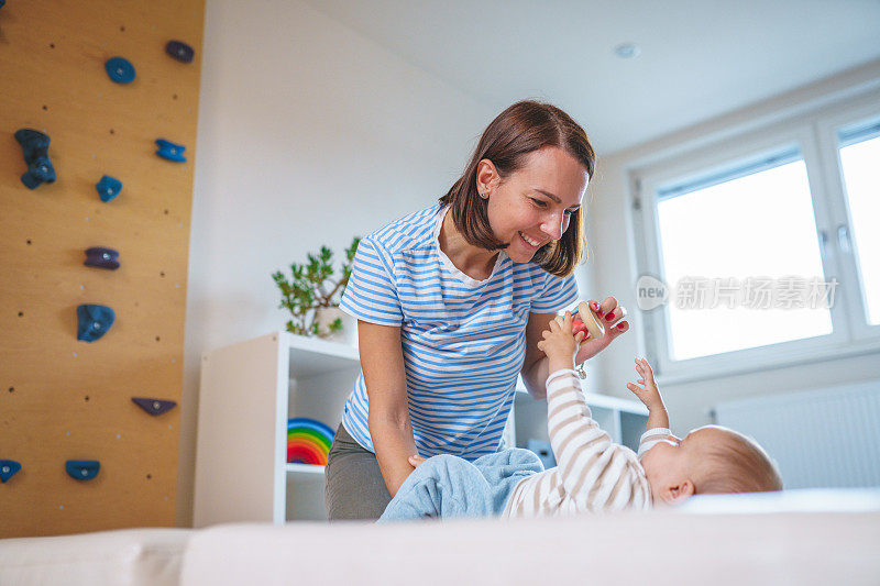 快乐的白人母亲在家里的游戏室和婴儿男孩玩