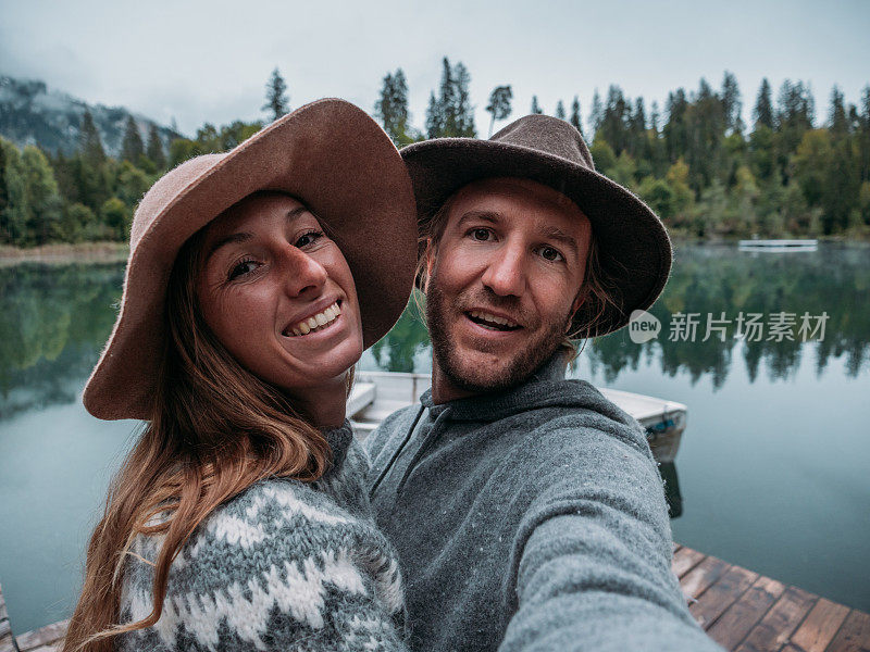 一对夫妇在高山湖上的木栈桥上自拍