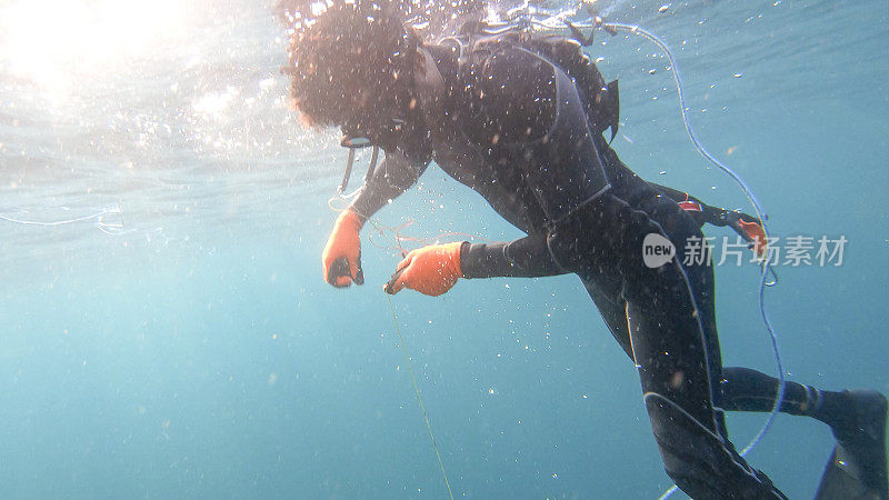 鱼叉渔民从一次成功的潜水中浮出水面的水下视图