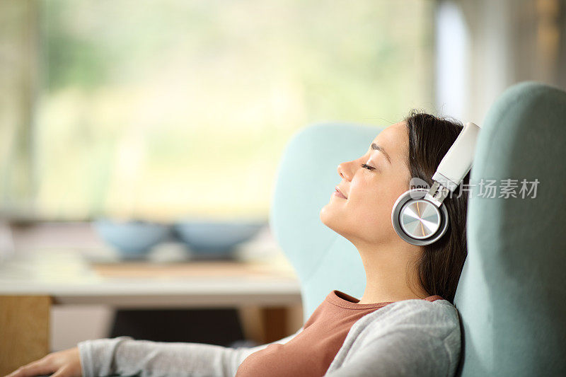 放松的女人戴着耳机坐在沙发上听音乐
