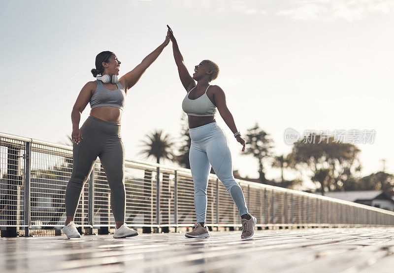 两名年轻女性外出健身时互相击掌的照片