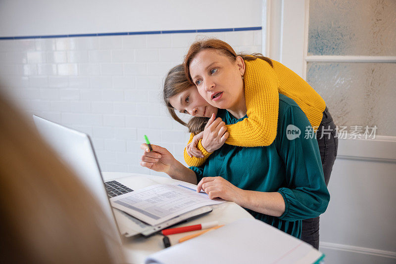 十几岁的女孩拥抱她的母亲，让她从远程电脑工作中分心