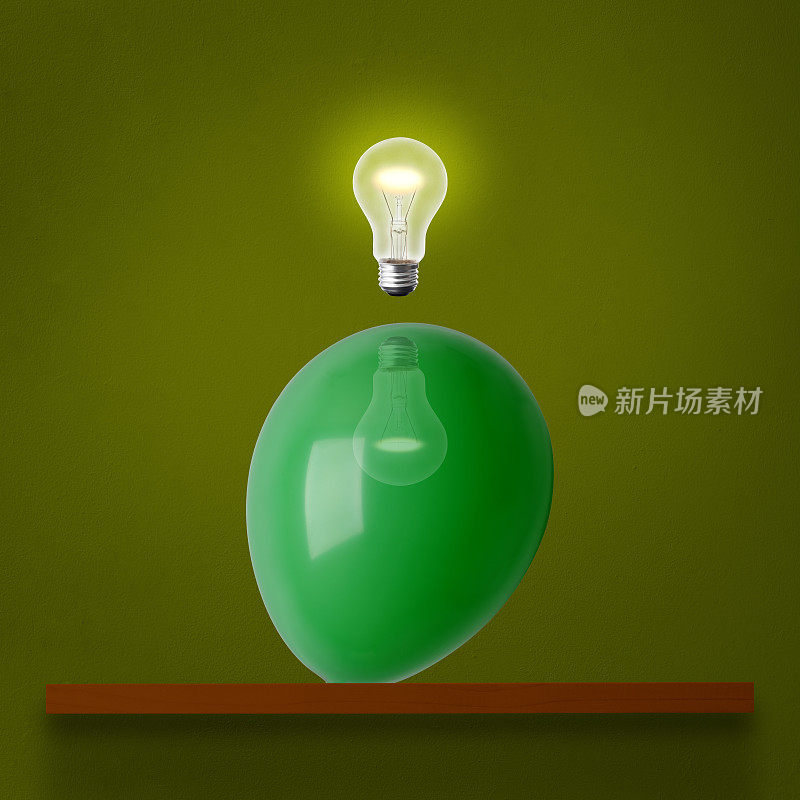 在架子上的绿色气球上方的半空中发光的灯泡。