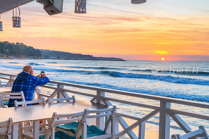 海滨风景-游客用他的智能手机拍摄海面上的日出