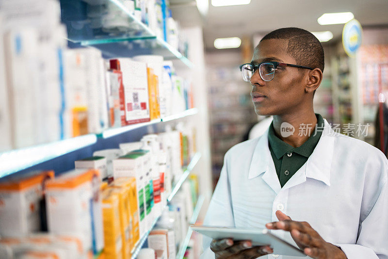 一名年轻的药剂师在药店用电子平板电脑检查货架