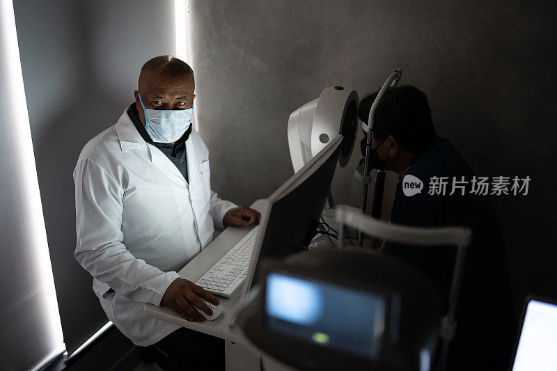 一名验光师戴着防护口罩在诊所检查病人的肖像