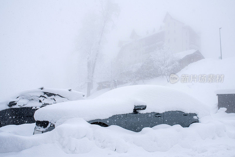暴风雪笼罩着停车场上积雪覆盖的汽车