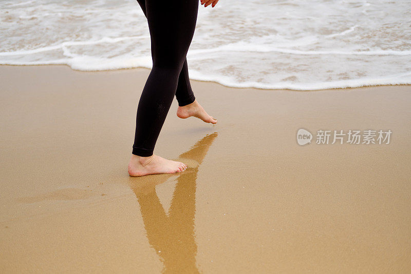 在海边赤脚走在沙滩上的女人可以促进腿部的血液循环