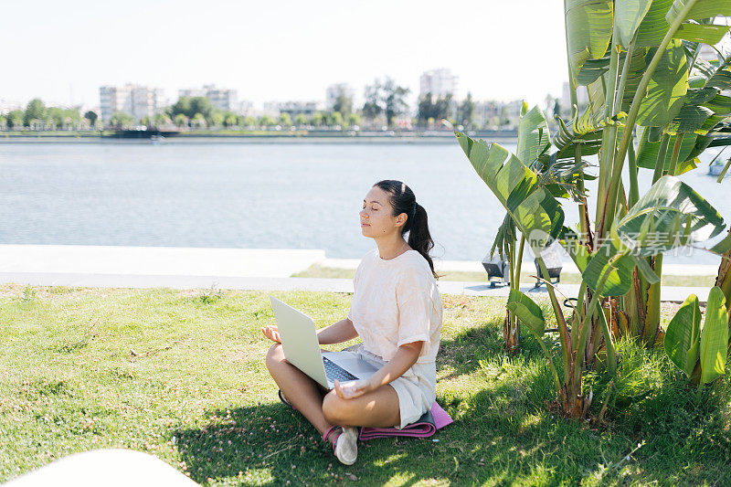 年轻女子在一个美丽的地方用笔记本电脑工作在大自然