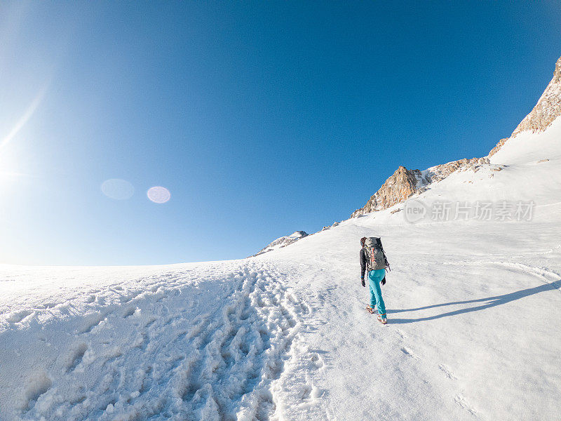 女登山者在雪道上攀登山峰