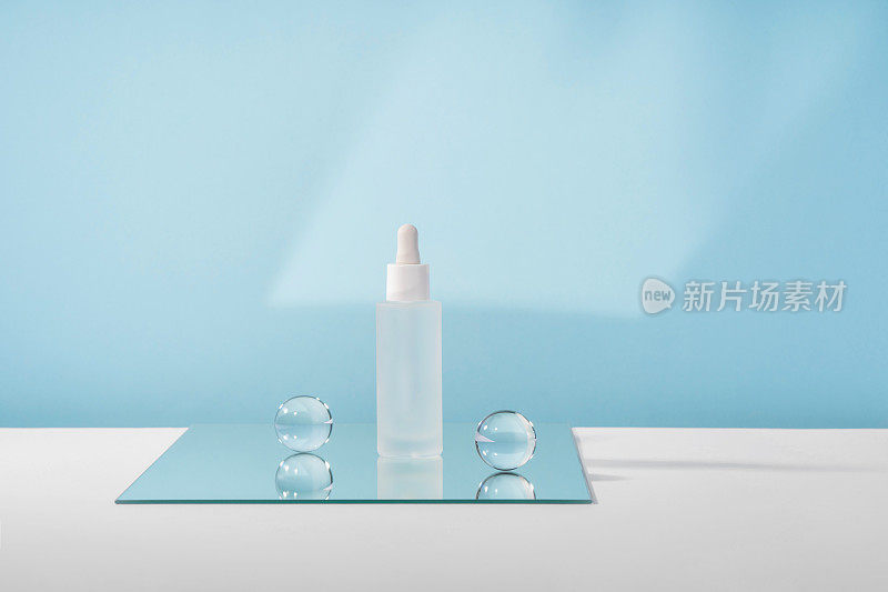 血清化妆品瓶与多肽和视黄醇镜面玻璃球在蓝色背景。玻尿酸化妆品产品模拟包装与时尚的道具。血清美容滴管模型