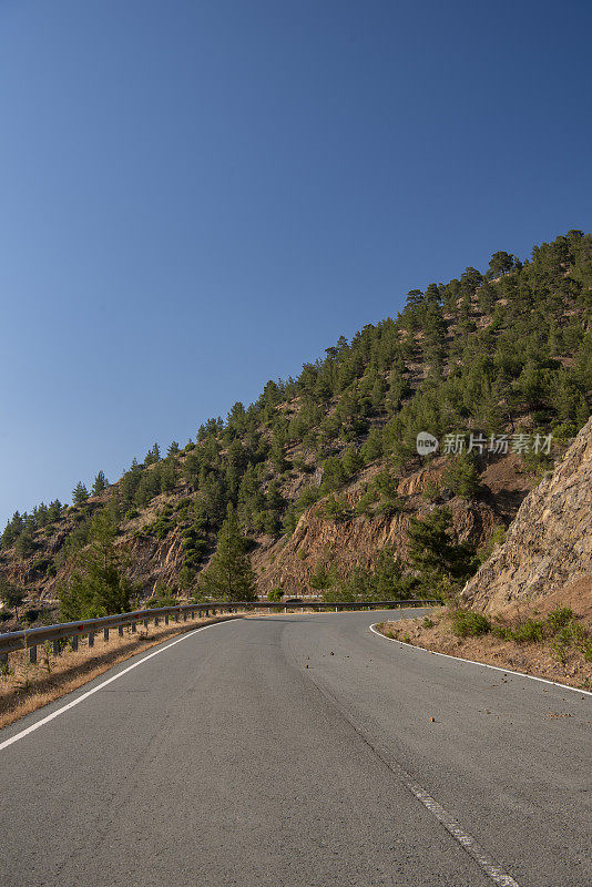 道路环绕在蜿蜒的山坡上，穿过陡峭的火山地形，地平线上是树木繁茂的山脊