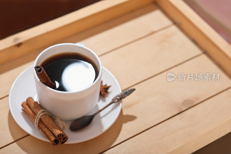 美式浓缩咖啡在经典的白色杯子。咖啡加肉桂和美味的木托盘。高角度视图。辛辣的冬季热饮