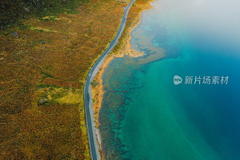 航拍的一辆汽车行驶在挪威翠绿色的海岸公路上