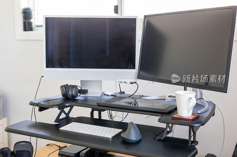 现代双显示器计算机在一个站立的办公桌在办公室