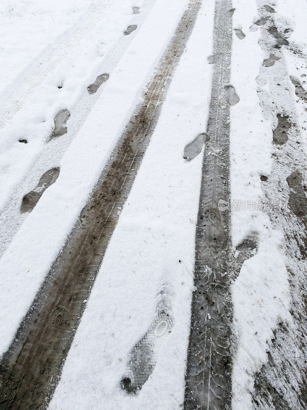 雪地里有轮胎印和人类脚印。