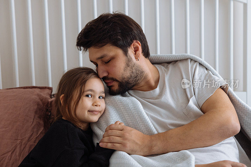 小女孩抱着爸爸，爱抚他，安慰他，让他平静下来。流感，疾病概念。