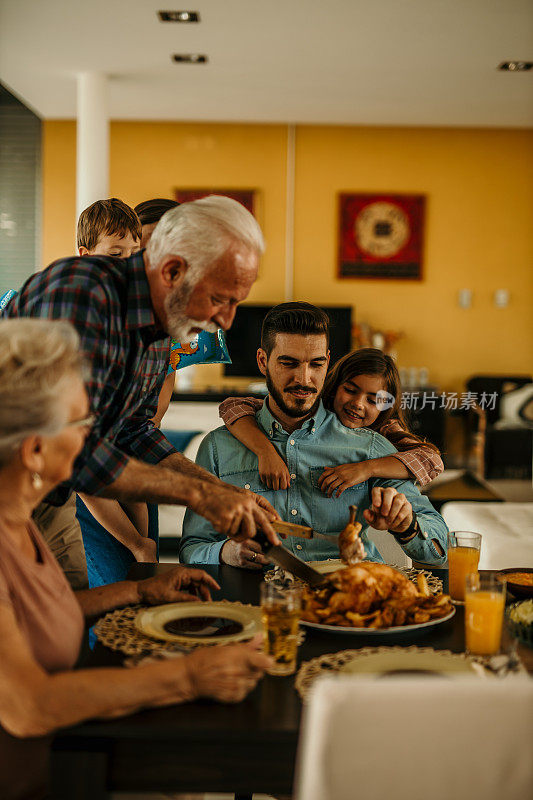 快乐的祖父在餐桌上吃家庭午餐时给他的孙女做意式烤面包