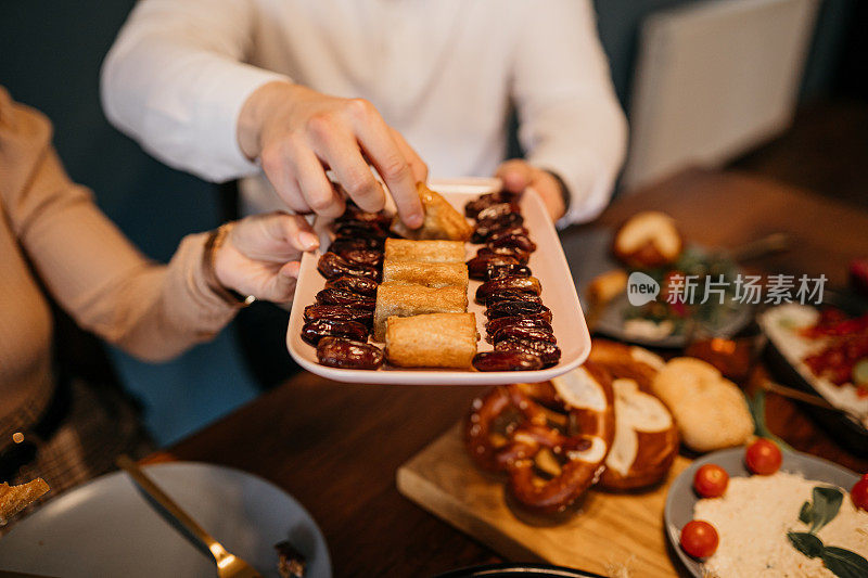 人类的手从斋月宴会上拿食物的特写