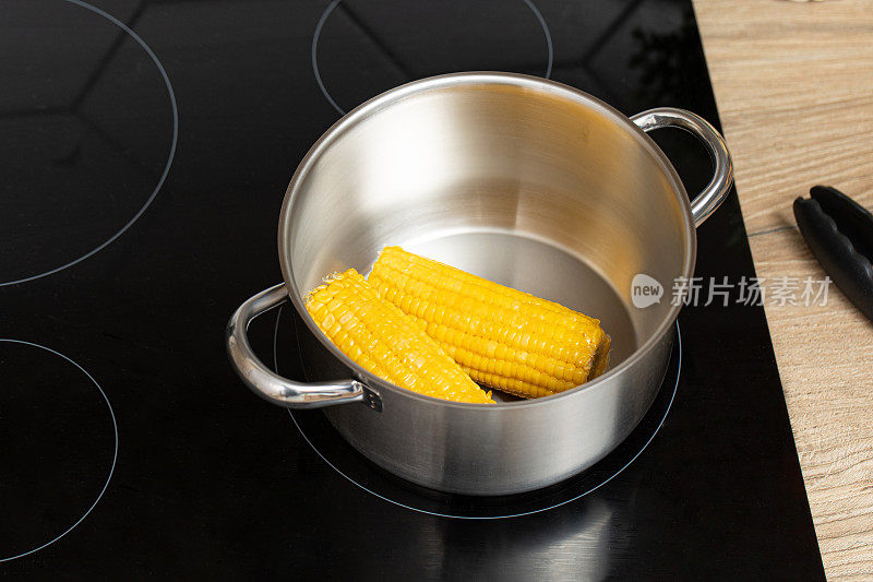 现代厨房用钳子从锅里煮玉米