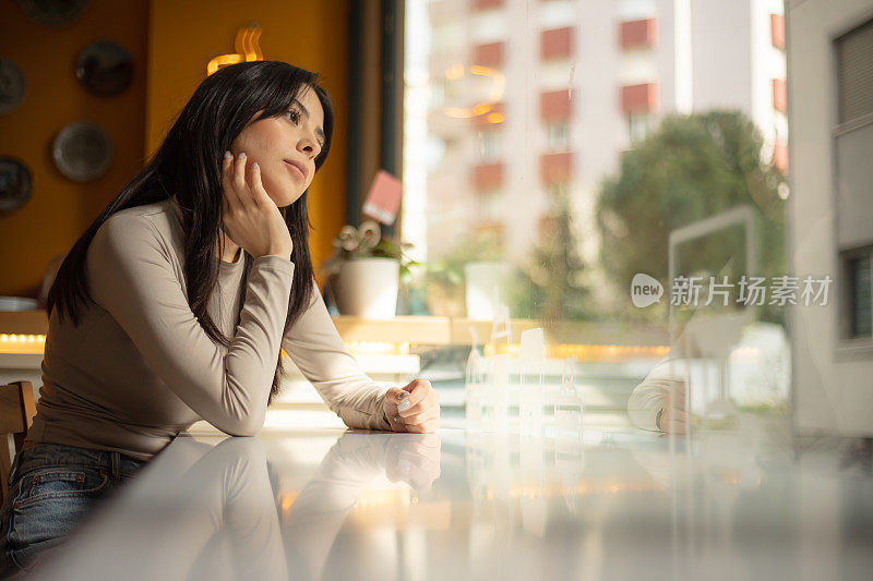 年轻黑发女子的肖像。她坐在咖啡店里。