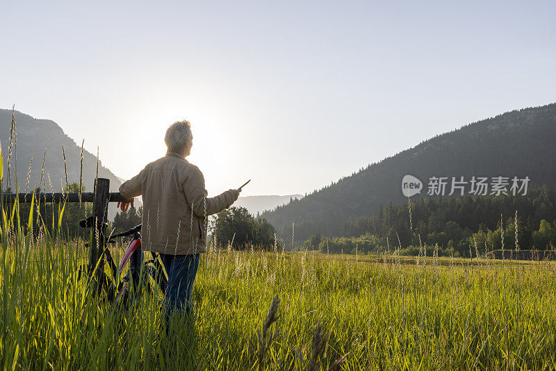 牧场主在木栅栏旁休息时使用数字平板电脑