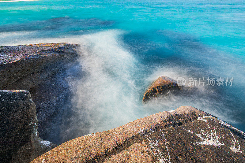 慢快门海岸场景，海水蓝色的海浪轻轻地冲刷着岩石