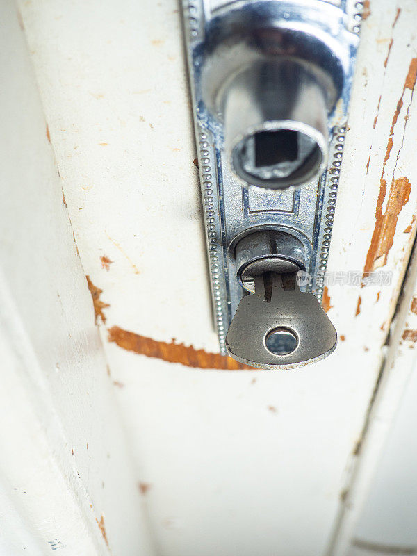 旧门的一部分。木头上的白漆正在脱落。表面油漆剥落。旧门把手。钥匙在门上的概念。