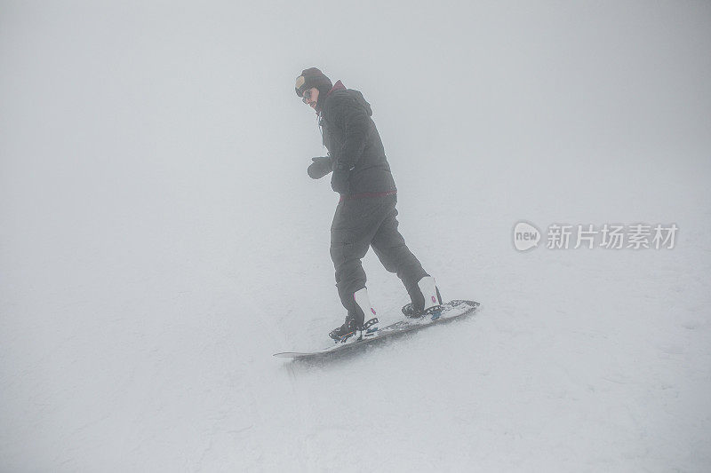 一名男子单板滑雪运动员在雾天从山上滑下