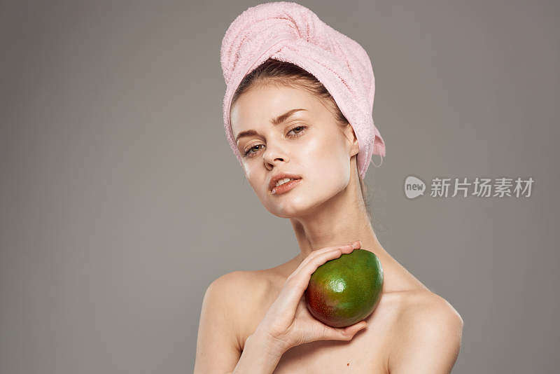 漂亮的女人用粉红色的毛巾在芒果的头上，裸露的肩膀维他命