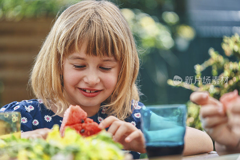 小女孩在外面的花园里吃新鲜的西瓜