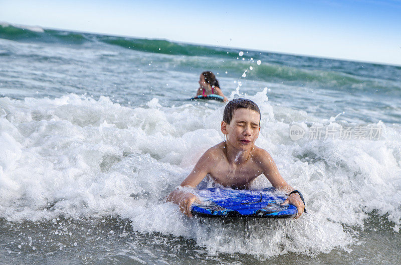 小孩子们在海滩上玩着小冲浪板