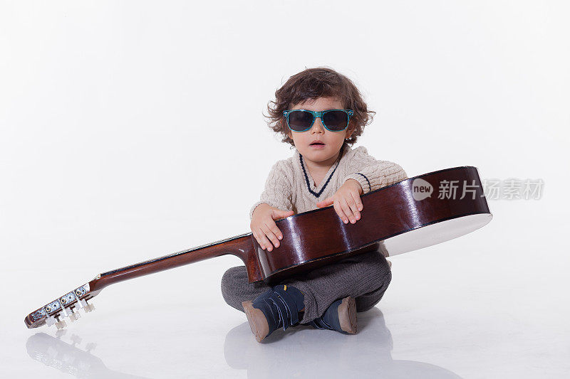 小男孩戴着墨镜弹古典吉他