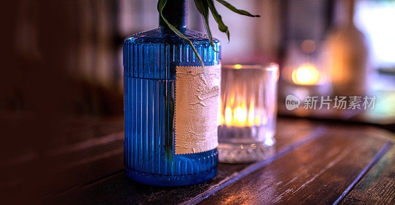 一个旧的蓝色罗纹瓶，标签看起来很旧，放在一张有copyspace的深色橡木桌子上，旁边是一根蜡烛