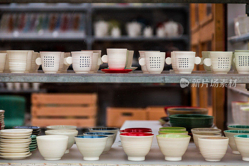 手工制作的彩色陶瓷咖啡杯和壶排成一排展示