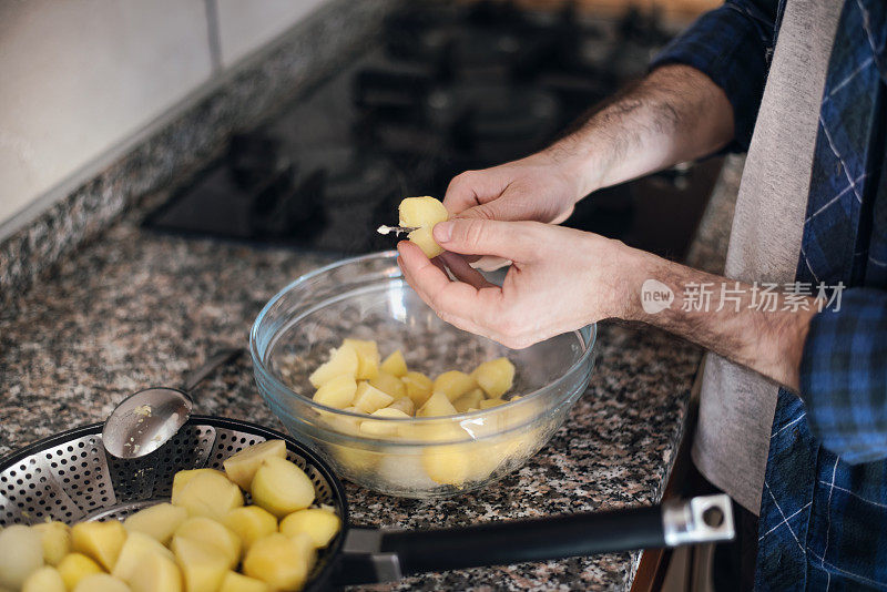 隔离烹饪:一名男子将土豆切好，放入沙拉碗中