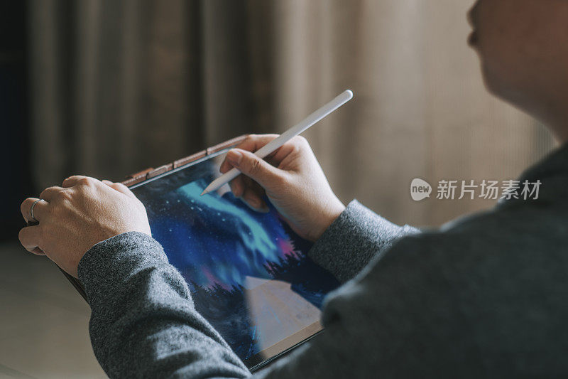 一位亚洲华人中年男子在家用平板电脑画画