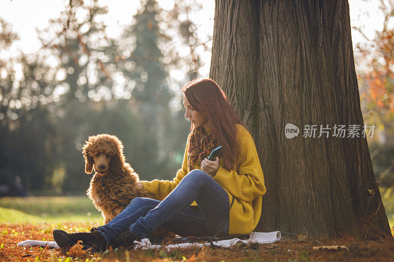 一个女人和她的狗在公园里野餐