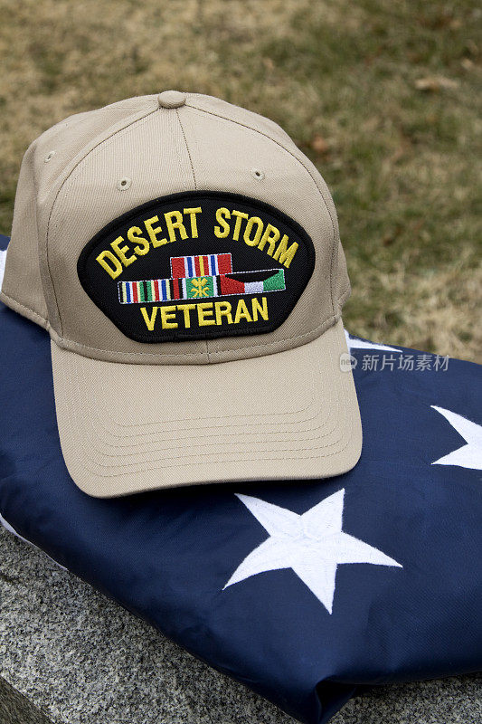 沙漠风暴老兵的帽子，美国国旗上的军事丝带在墓地的墓碑上。