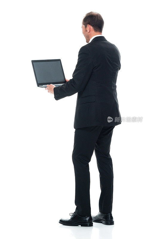 白人年轻男性穿着商务装站在白色背景前使用电脑