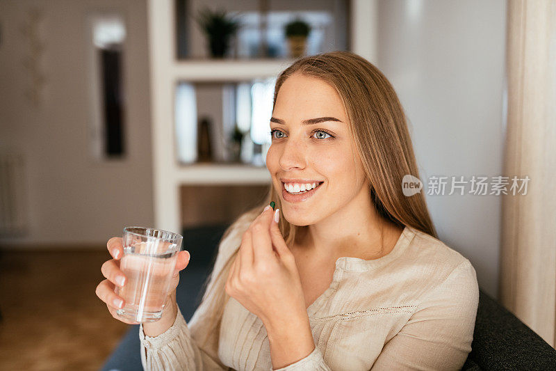 年轻健康的金发女子正在服用补品